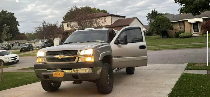 Chevy pickup truck with headlights on parked in suburban residential neighborhood