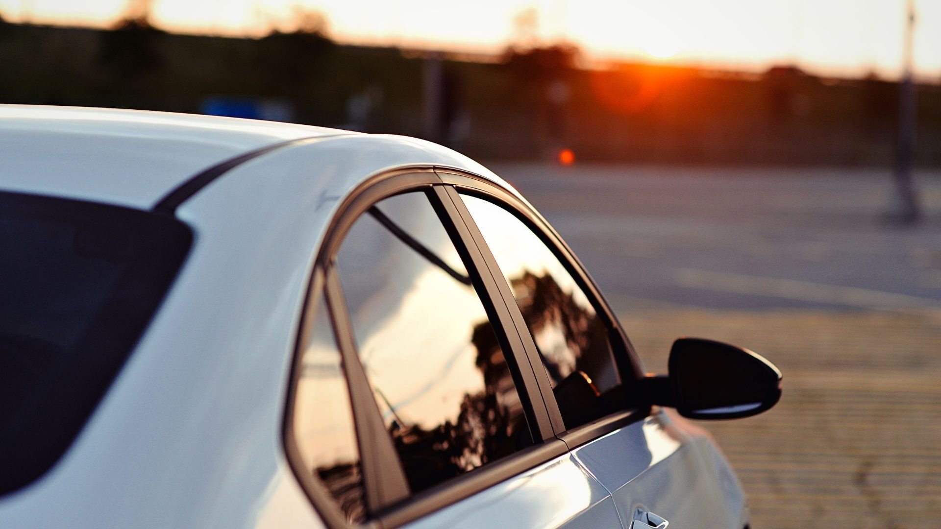 White car with sunset reflecting in window at golden hour