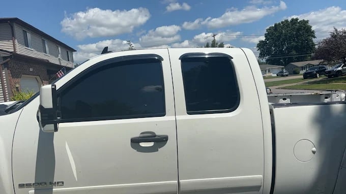 White pickup truck parked on residential street with cloudy blue sky