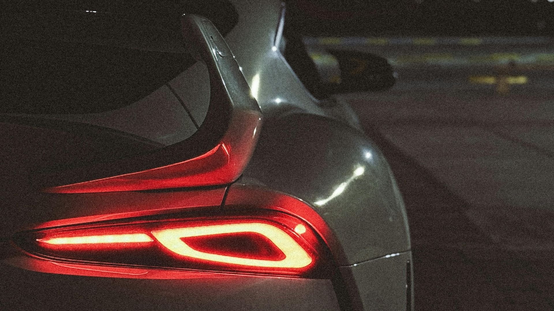 Sleek car taillight glowing red in dark, modern automotive design